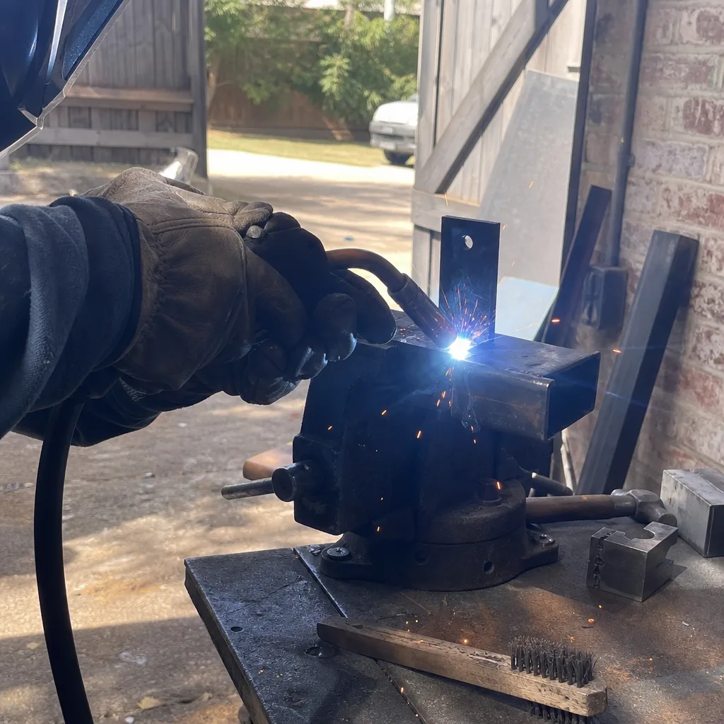 Professional welder repairing metal gate parts on a workbench in Keller, TX
